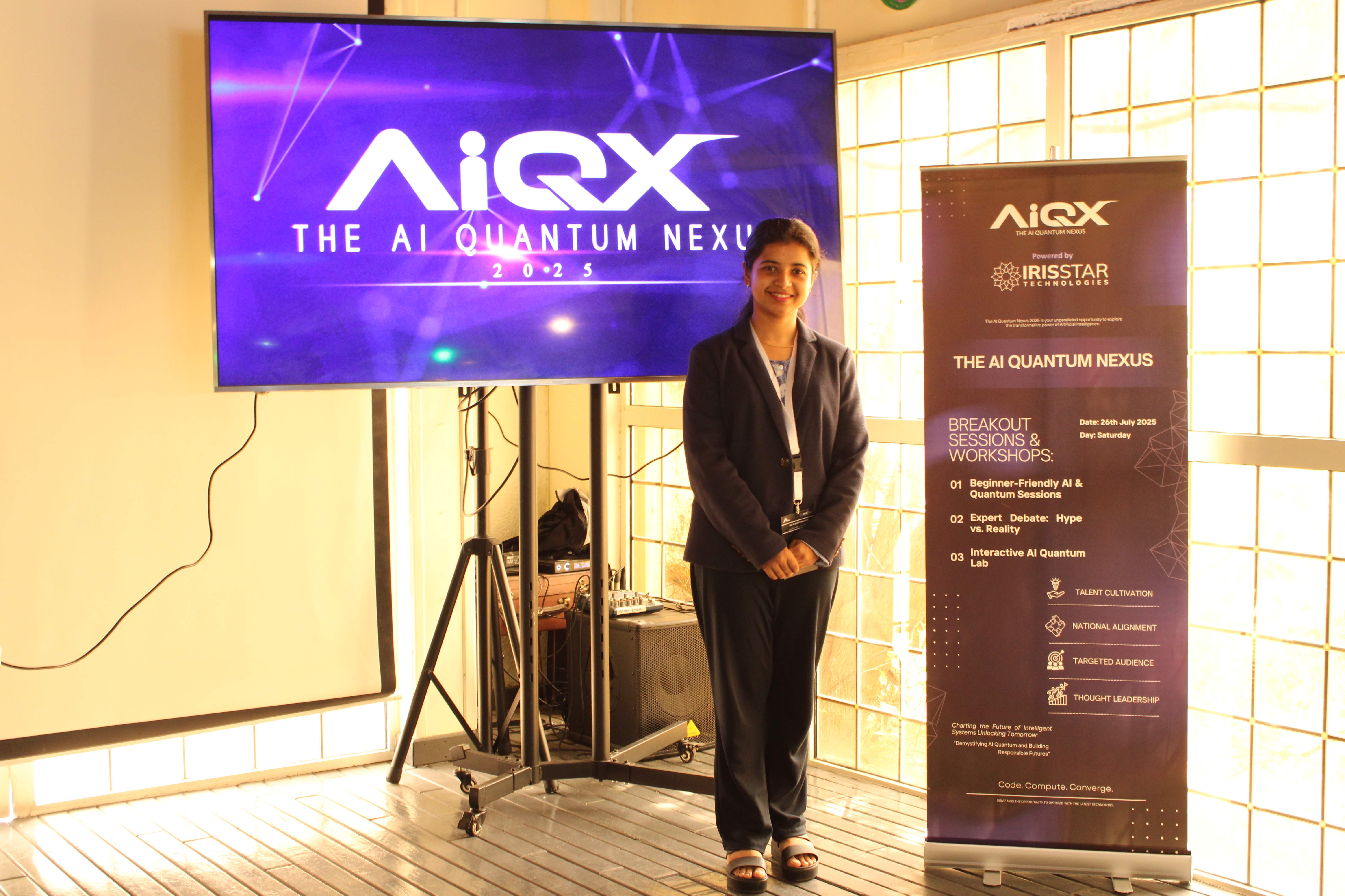 Speaker in navy blazer near AIQX banner