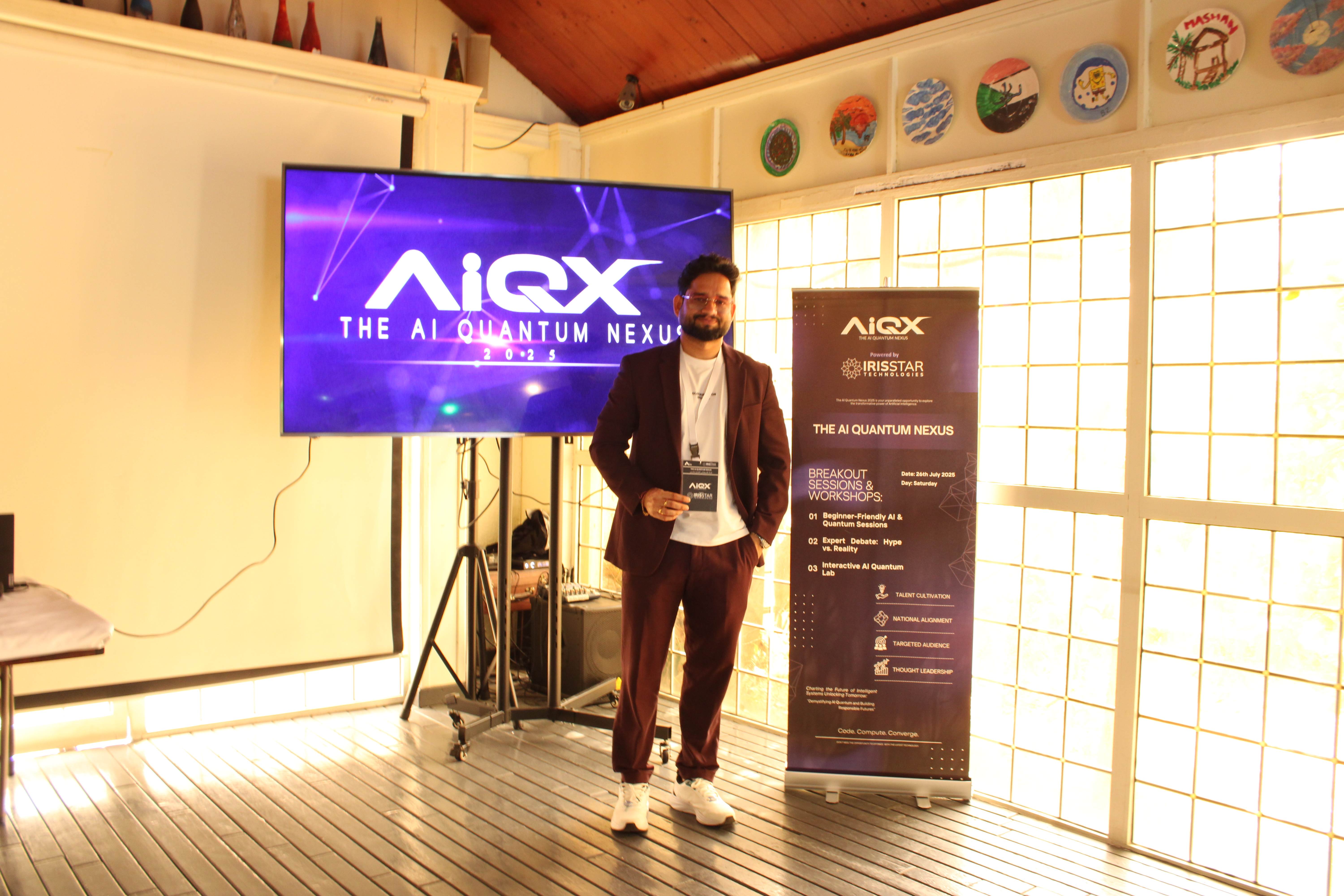 Speaker in maroon suit near AIQX banner