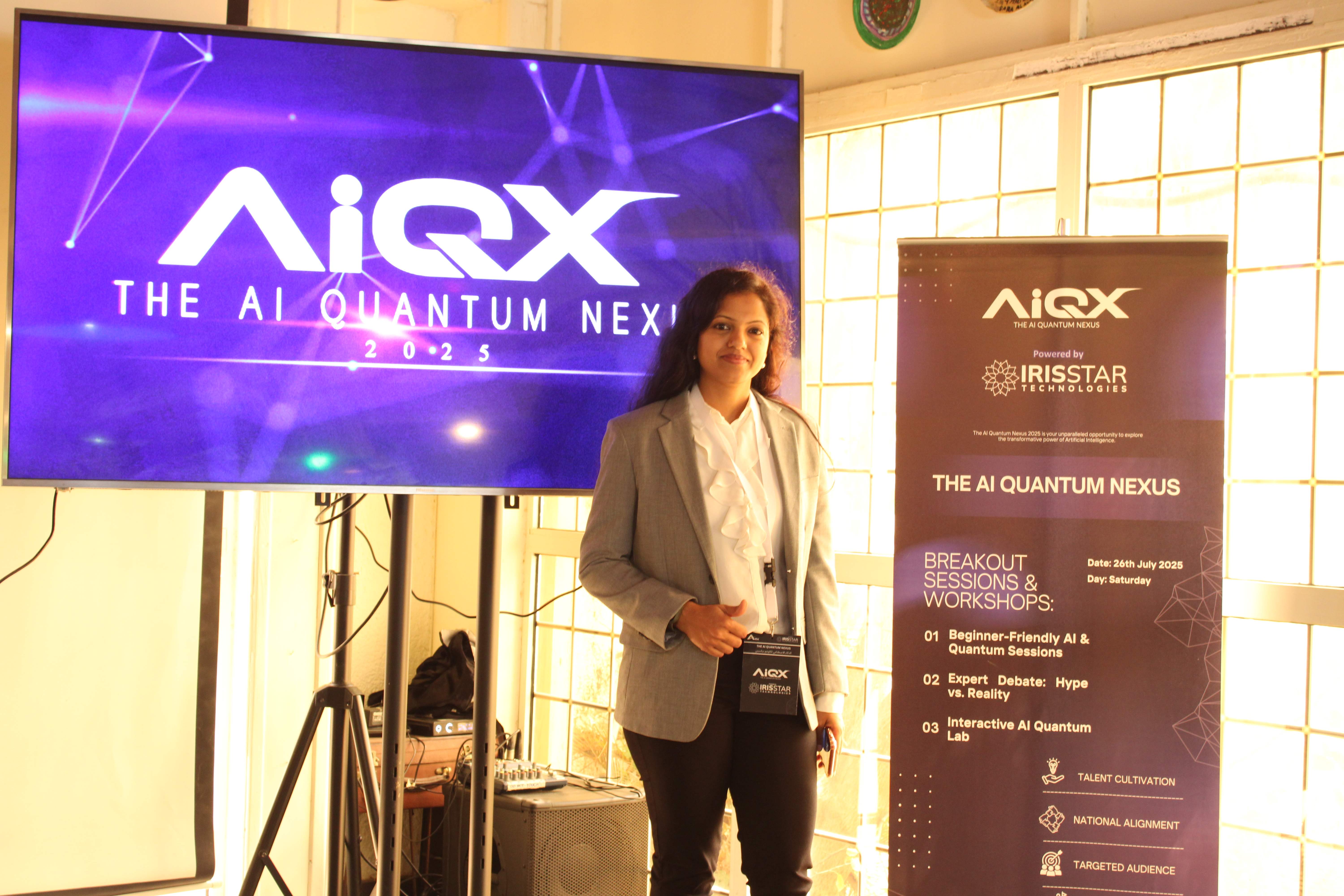 Speaker in grey blazer near AIQX banner